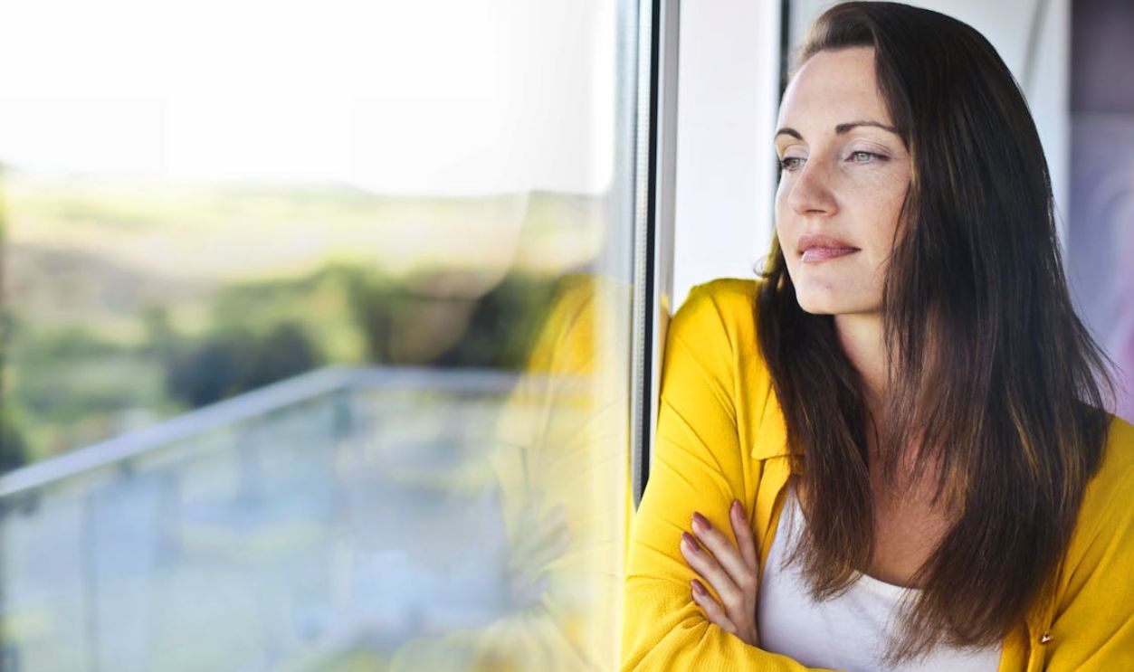 Woman in Yellow Long Sleeve Leaning on Glass Window