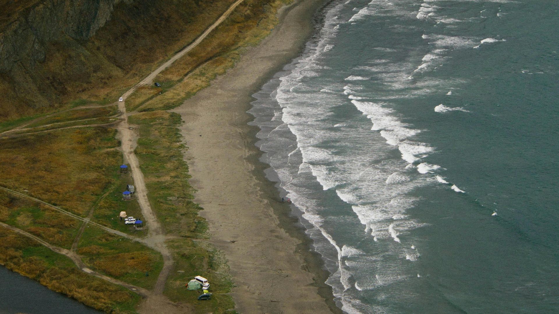 Stunning aerial view of an isolated beach, waves crashing along the rugged shore.