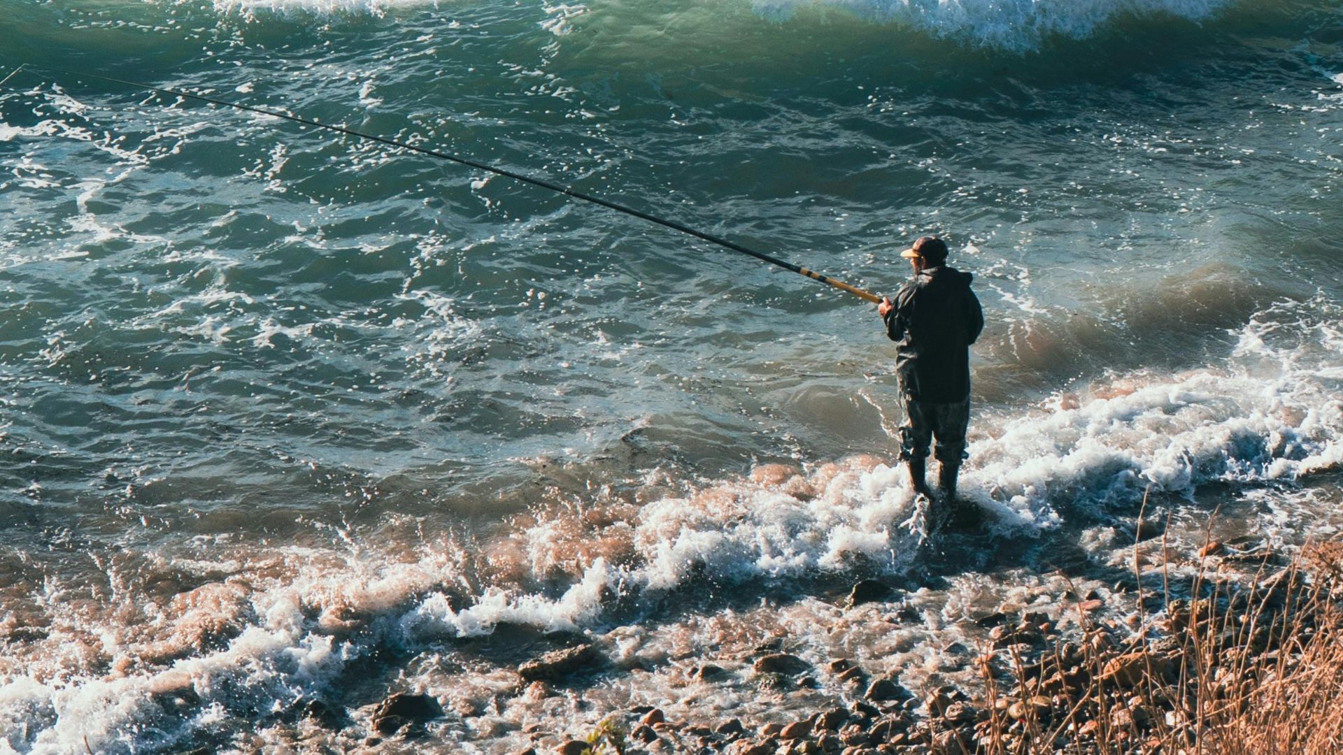 A man fishes at the shore of Al Hoceima, Morocco, capturing the essence of a calm outdoor adventure.