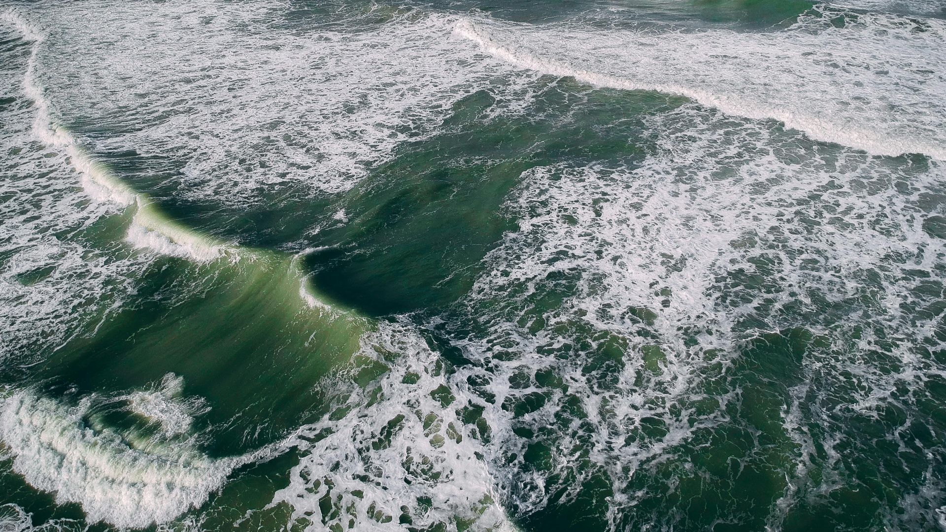 Breathtaking aerial shot of ocean waves forming intricate patterns and textures.