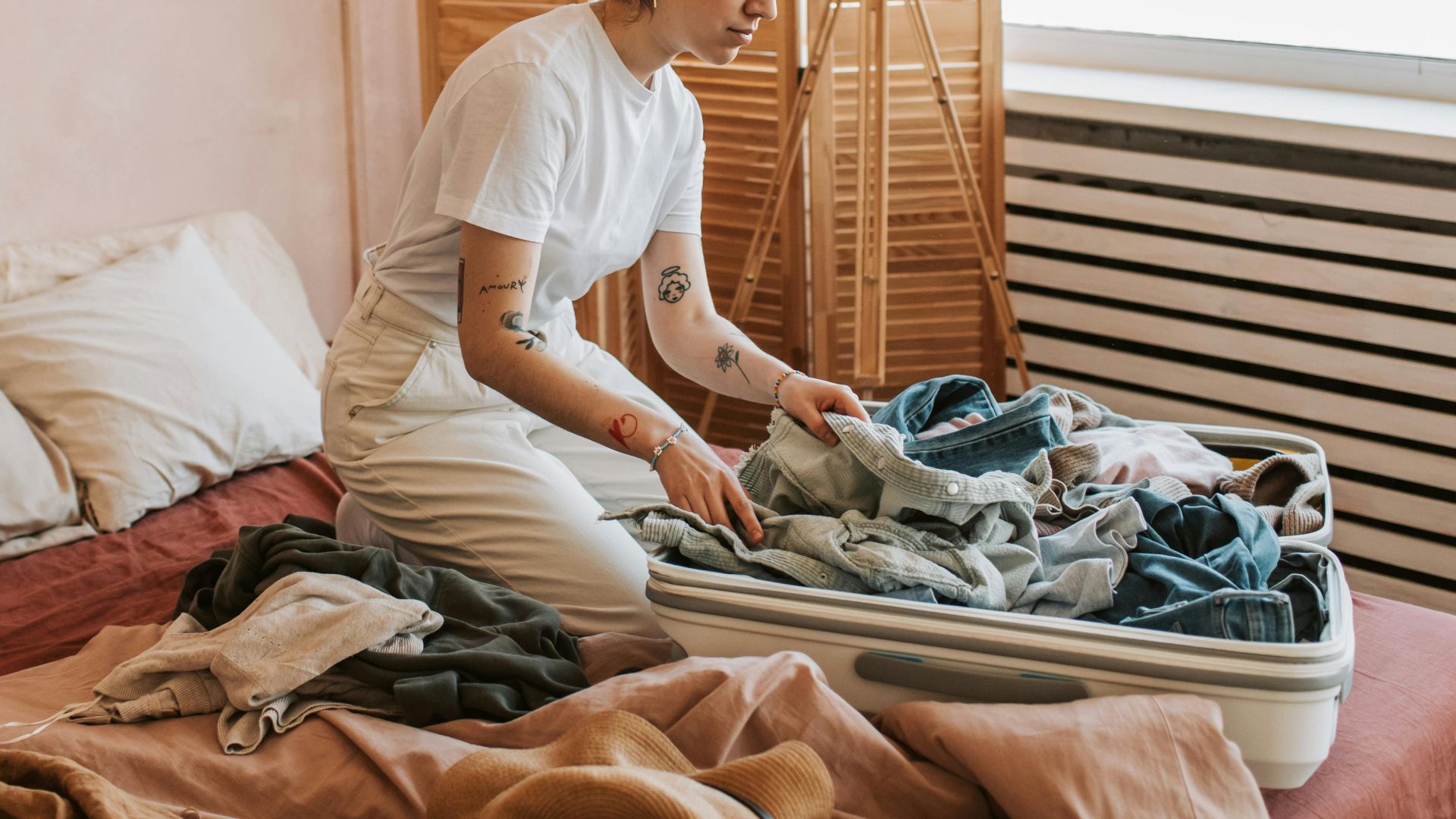 Woman packing suitcase in a cozy bedroom, preparing for travel. Relaxed and intimate setting.