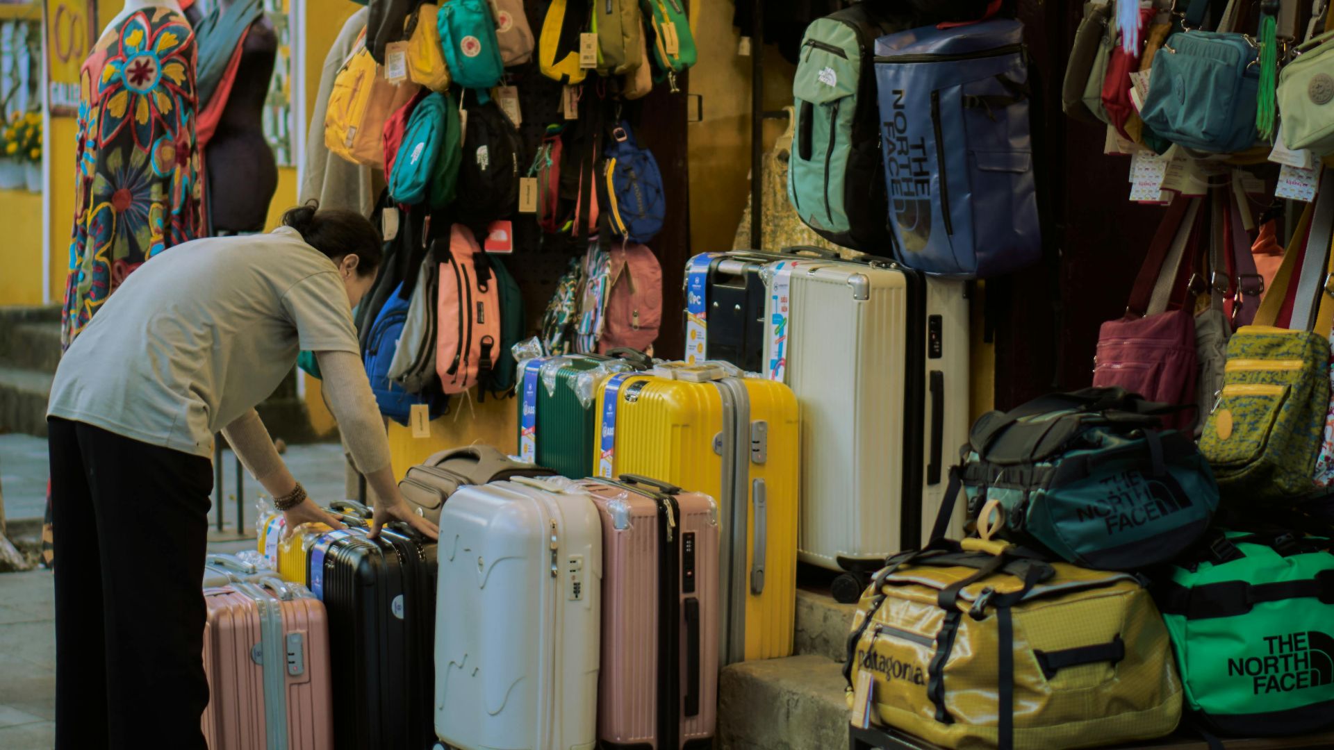 Street market scene with various colorful bags and luggage on display, offering an urban shopping experience.