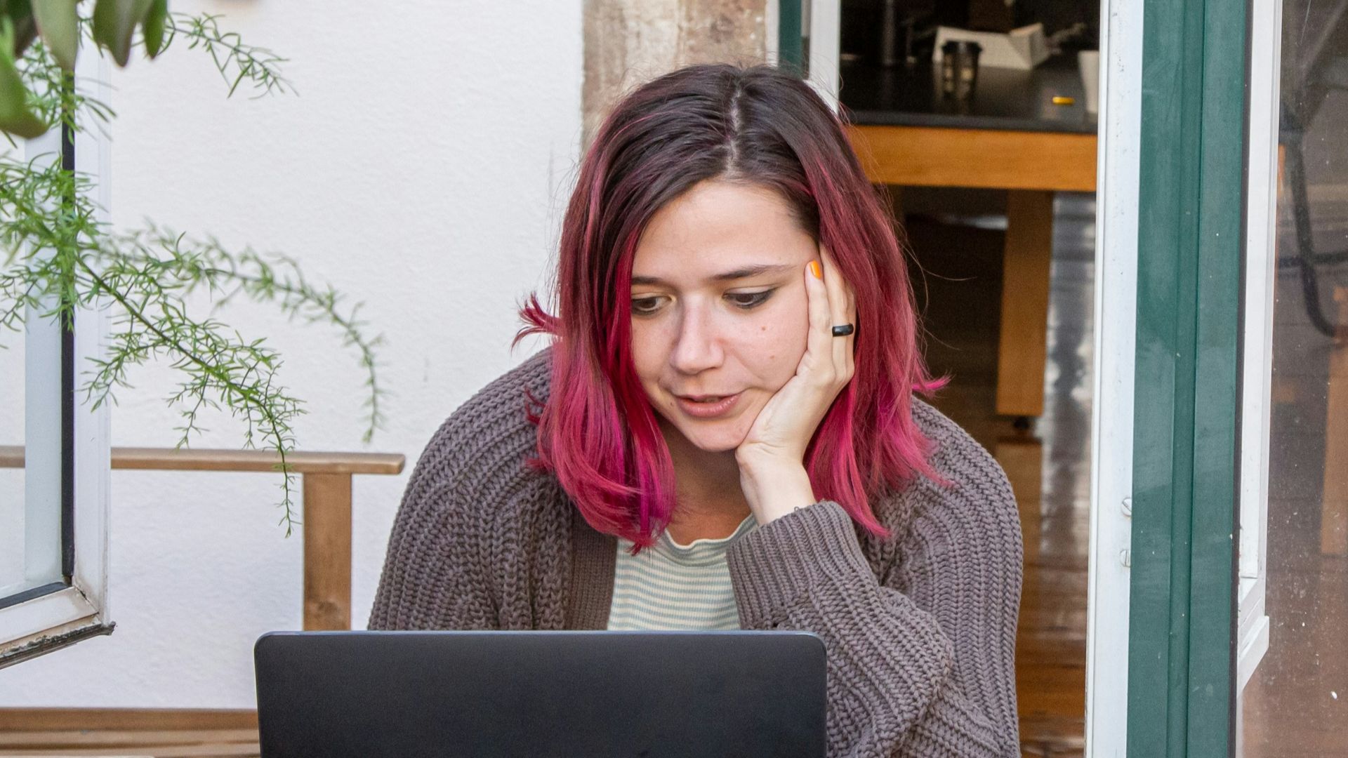 a woman with pink hair is looking at a laptop