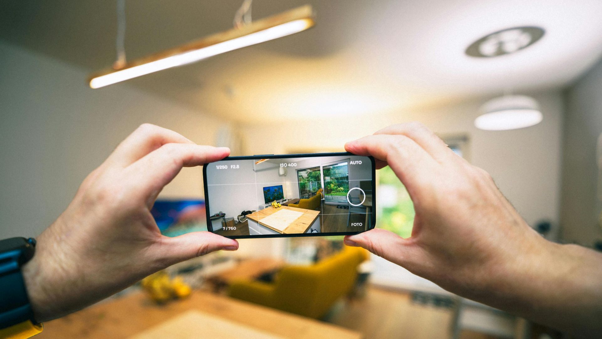 Hands capturing a modern living room interior with a smartphone.