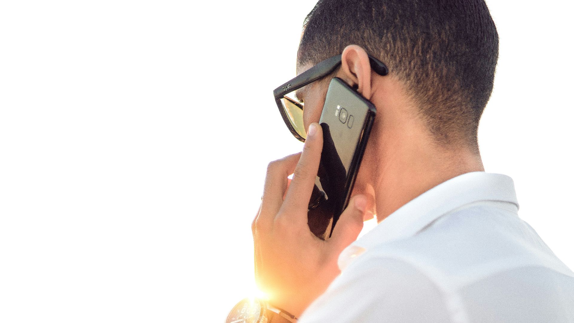 man holding smartphone standing in front of calm body of water