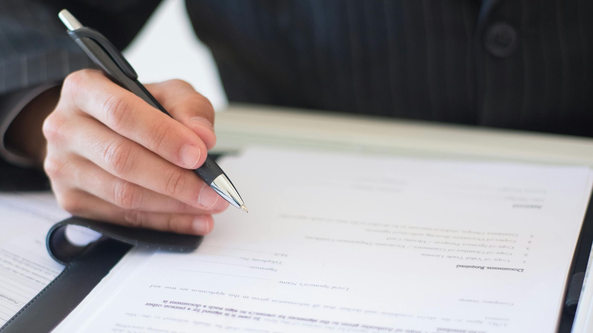 Close-up of a business professional signing documents in an office setting.