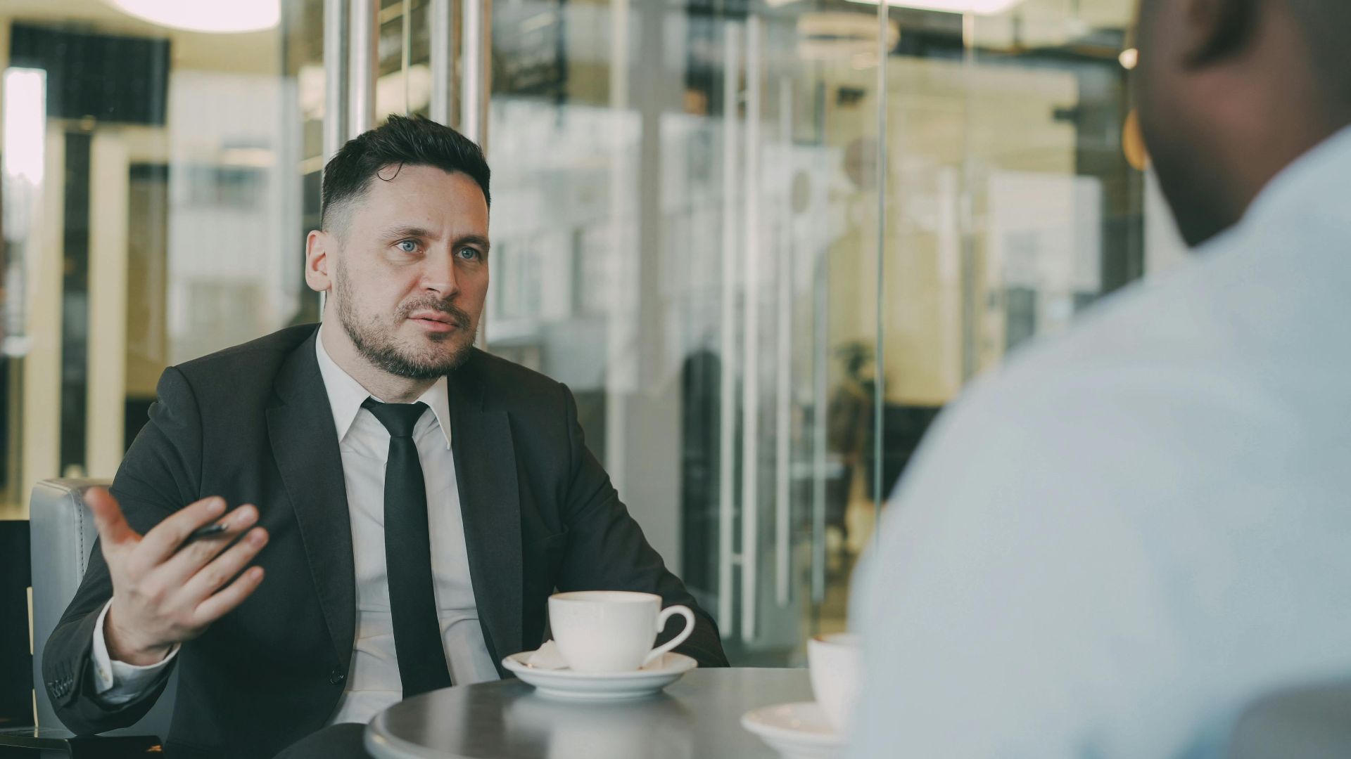 Two businessmen having a professional discussion over coffee in a modern cafe setting.