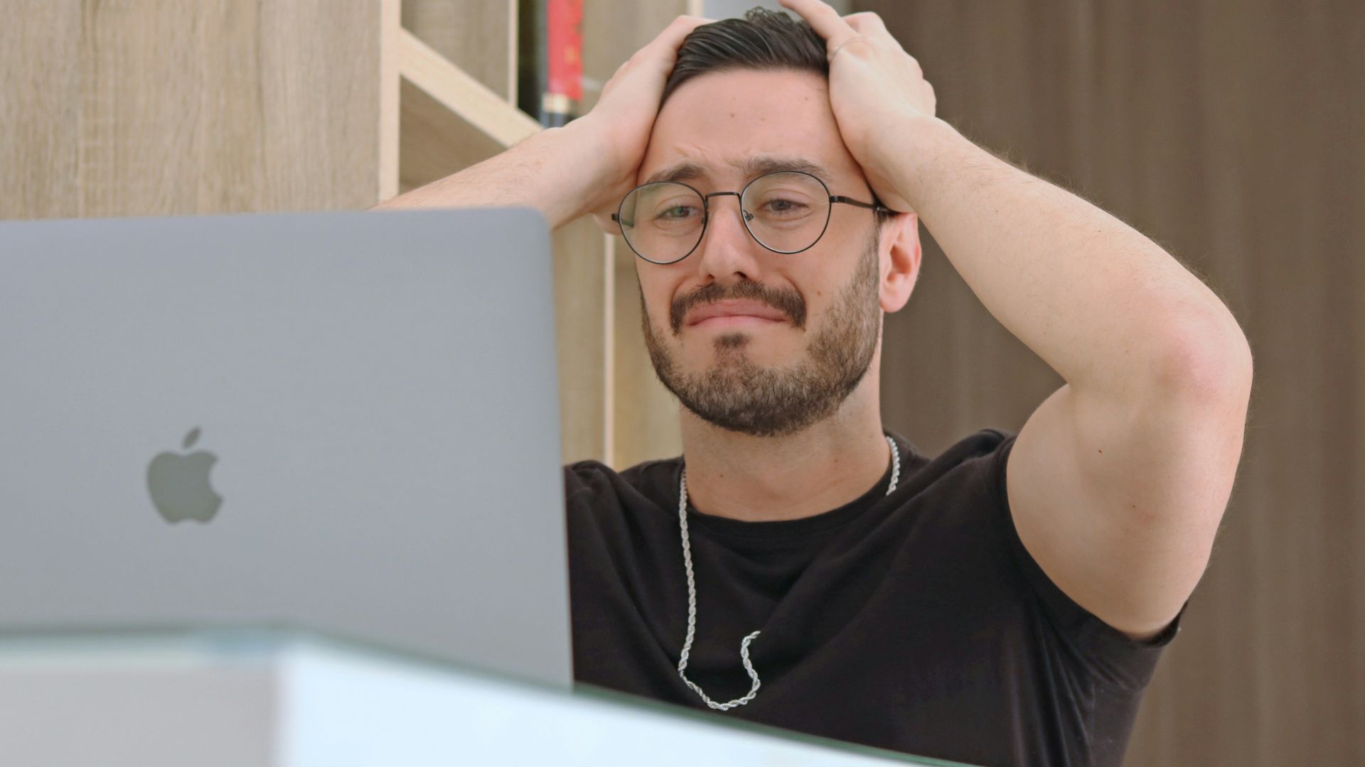 a man with glasses is looking at a laptop