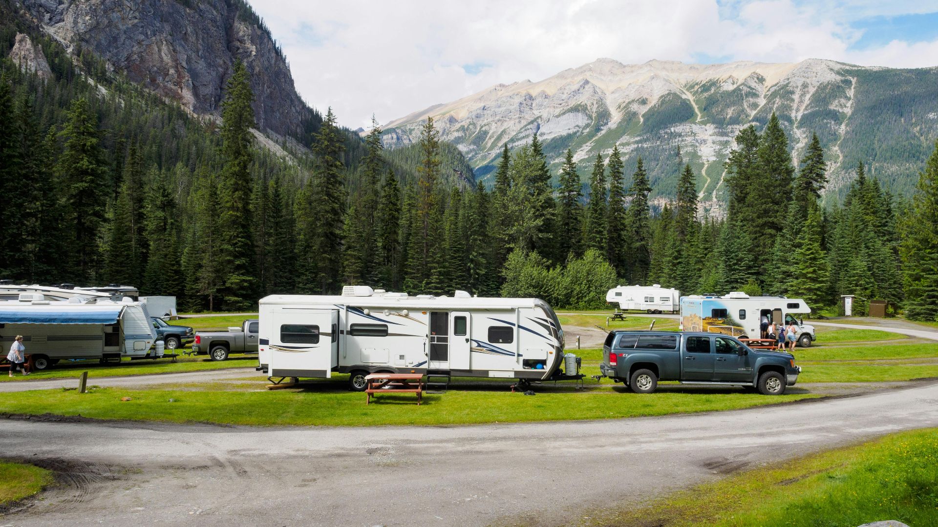 A beautiful campsite featuring RVs amidst lush forests and towering mountains for a peaceful getaway.