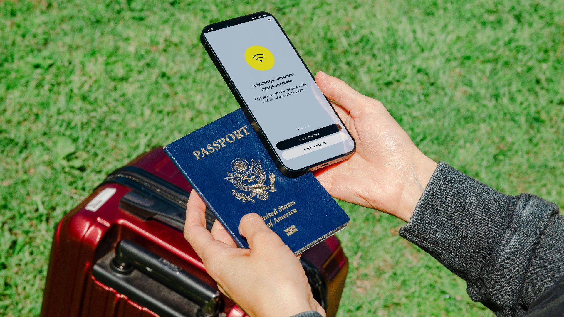 Close-up of hands holding a passport and smartphone with lost connection outdoors beside luggage.
