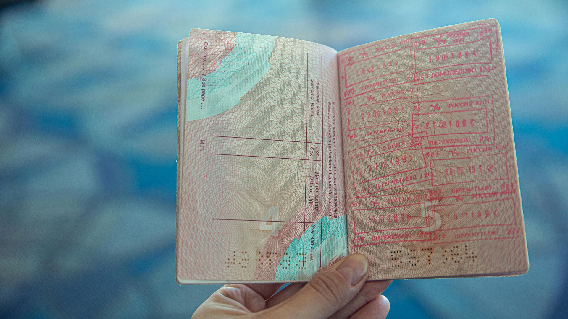 Close-up view of an open passport displaying various travel stamps in an airport setting.