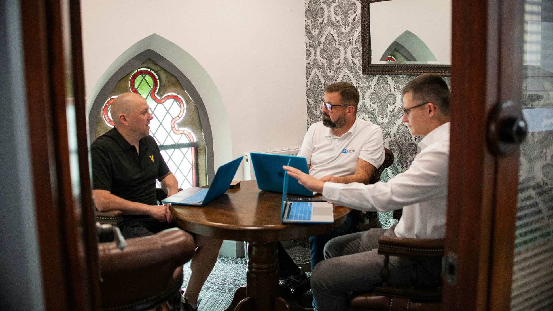 Three men in a meeting with laptops.