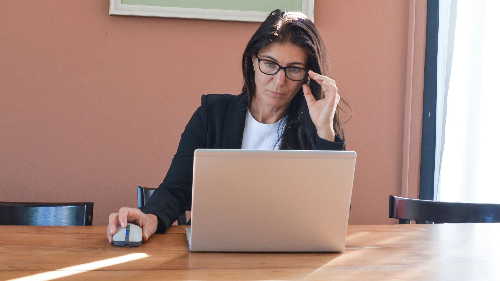Woman in glasses working on laptop at desk