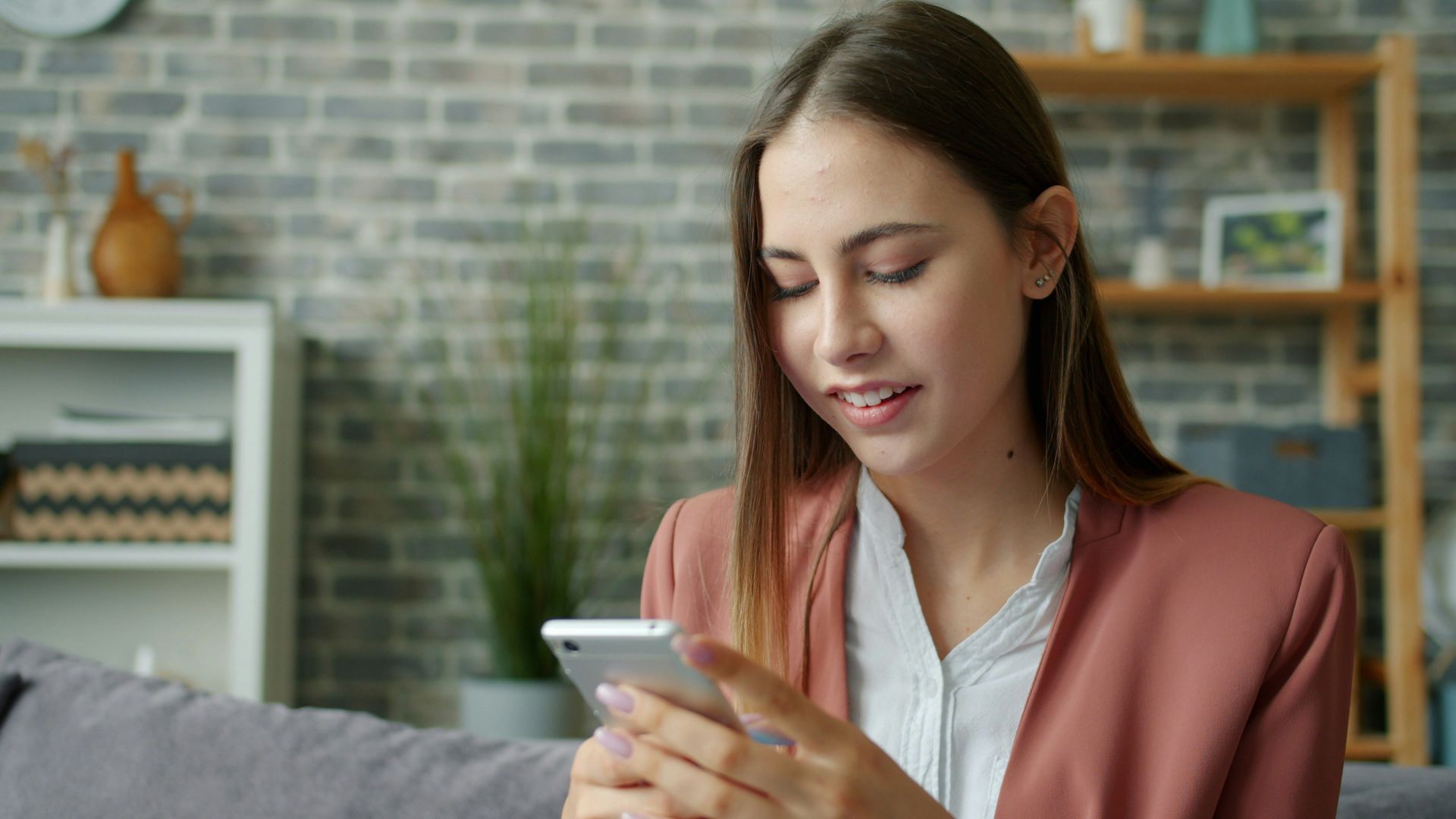 Young woman looking at her smartphone on a couch.