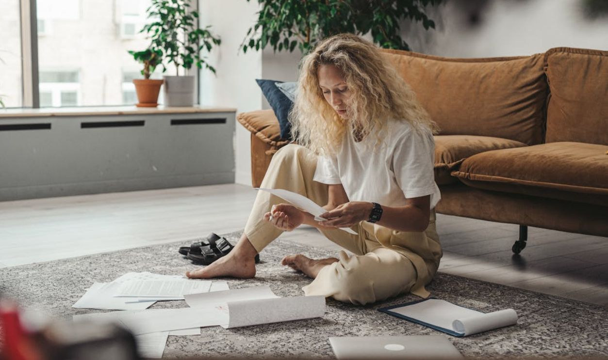 Woman in White Shirt Sitting on Floor Looking at Paperworks