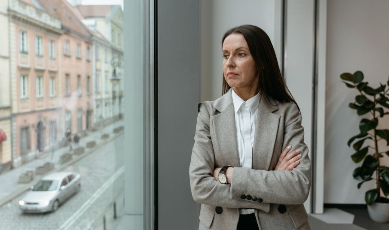 Woman in Gray Blazer With Crossed Arms Looking Outside