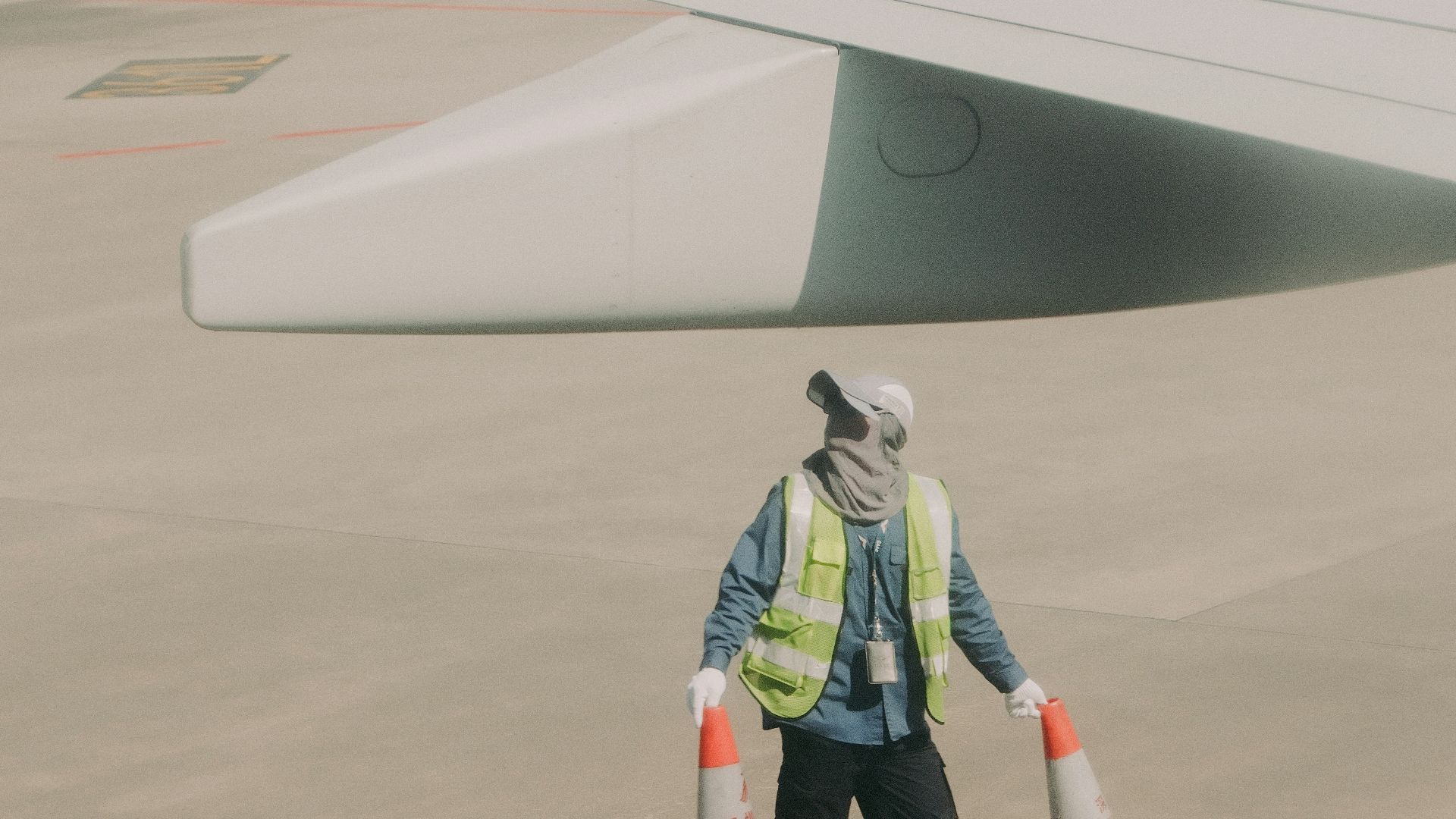 Worker with traffic cones near airplane wing