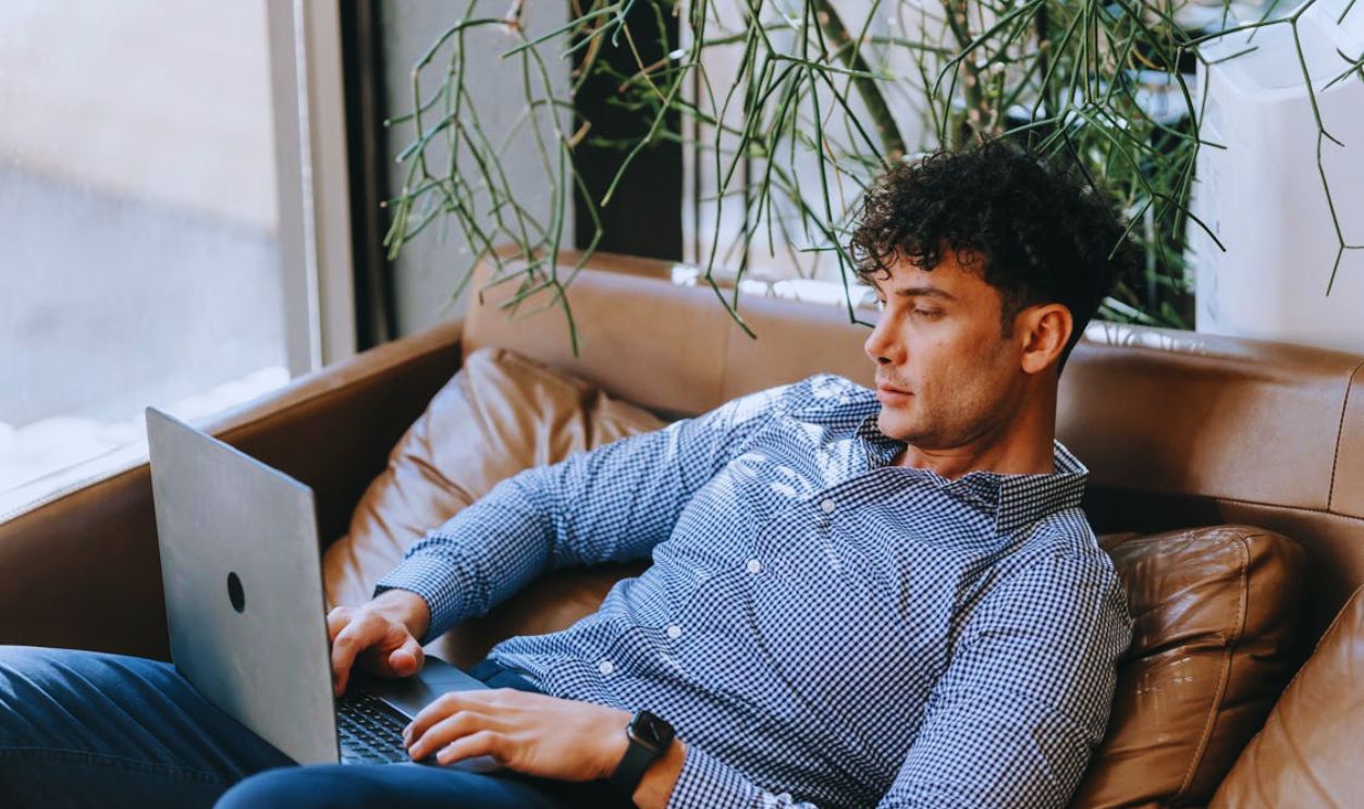 A Man Using a Laptop while Sitting on a Couch