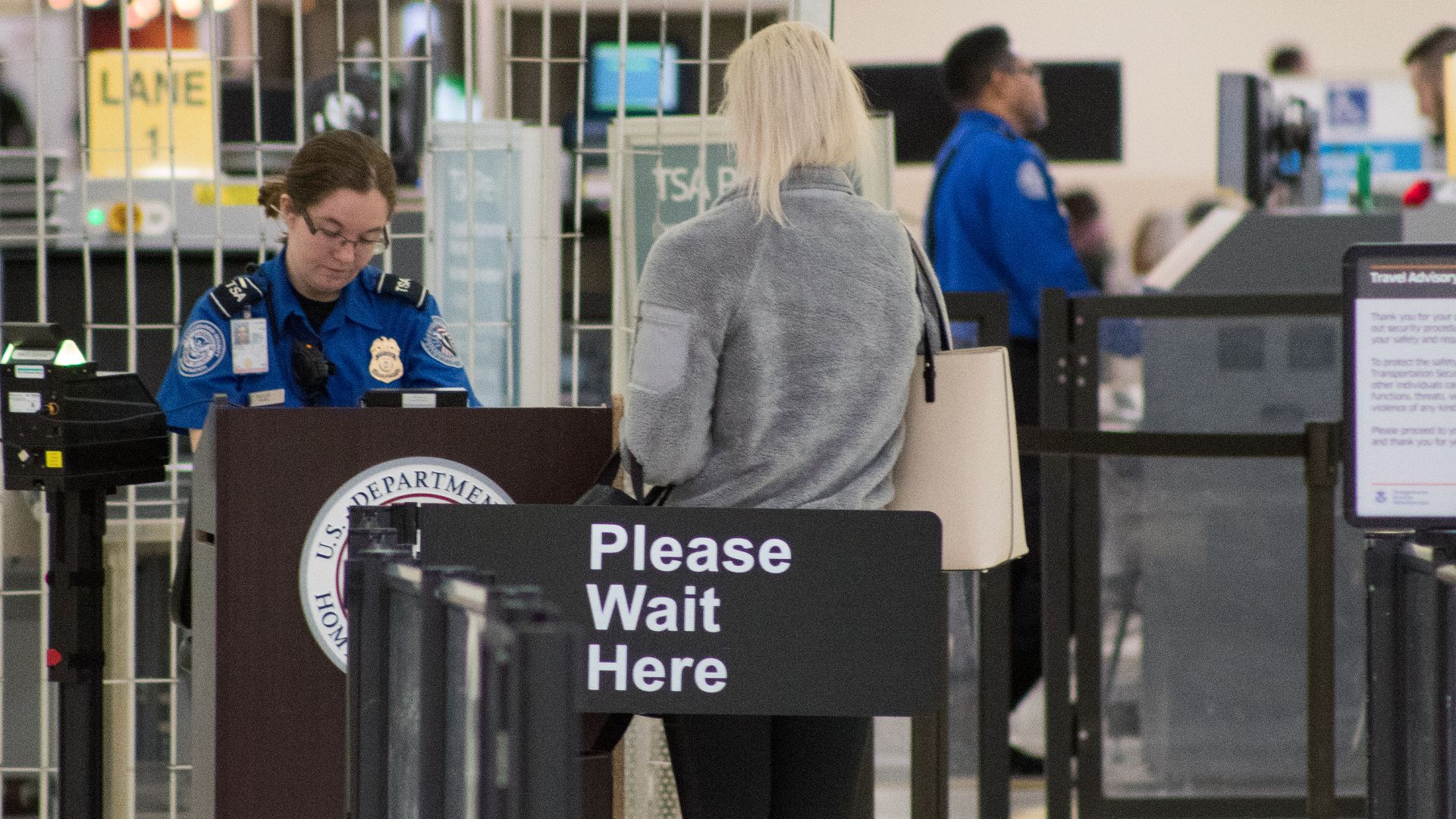 A Transportation Security Administration agent at a checkpoint verifying passenger identification, John Glenn Columbus International Airport