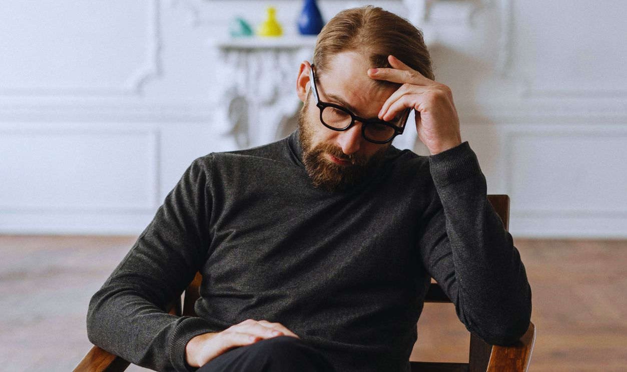 Man in Black Sweater Sitting on Brown Wooden Chair