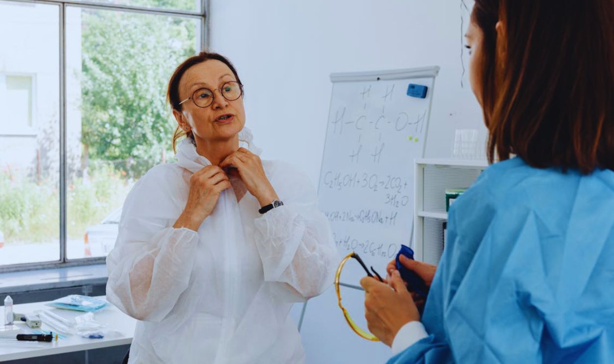 Women Wearing Personal Protective Equipment Standing while Having a Conversation