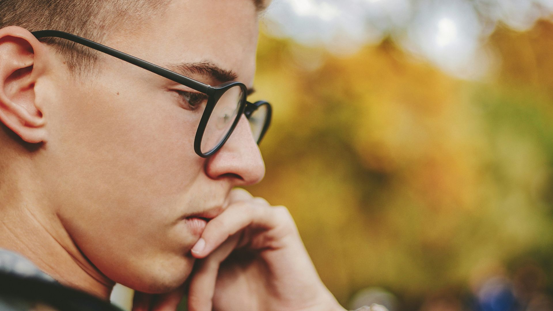 boy with black framed eyeglasses holding face
