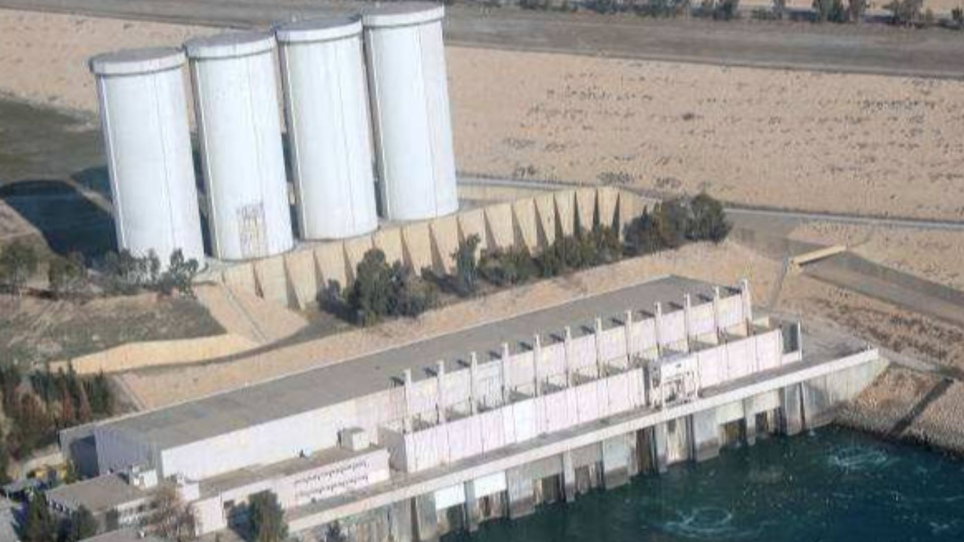The hydroelectric power plant at Mosul Dam with four surge tanks in background