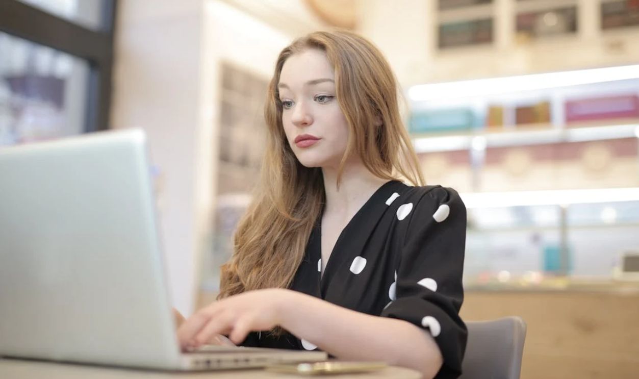 Woman in Black and White Polka Dots Dress Using Silver Laptop