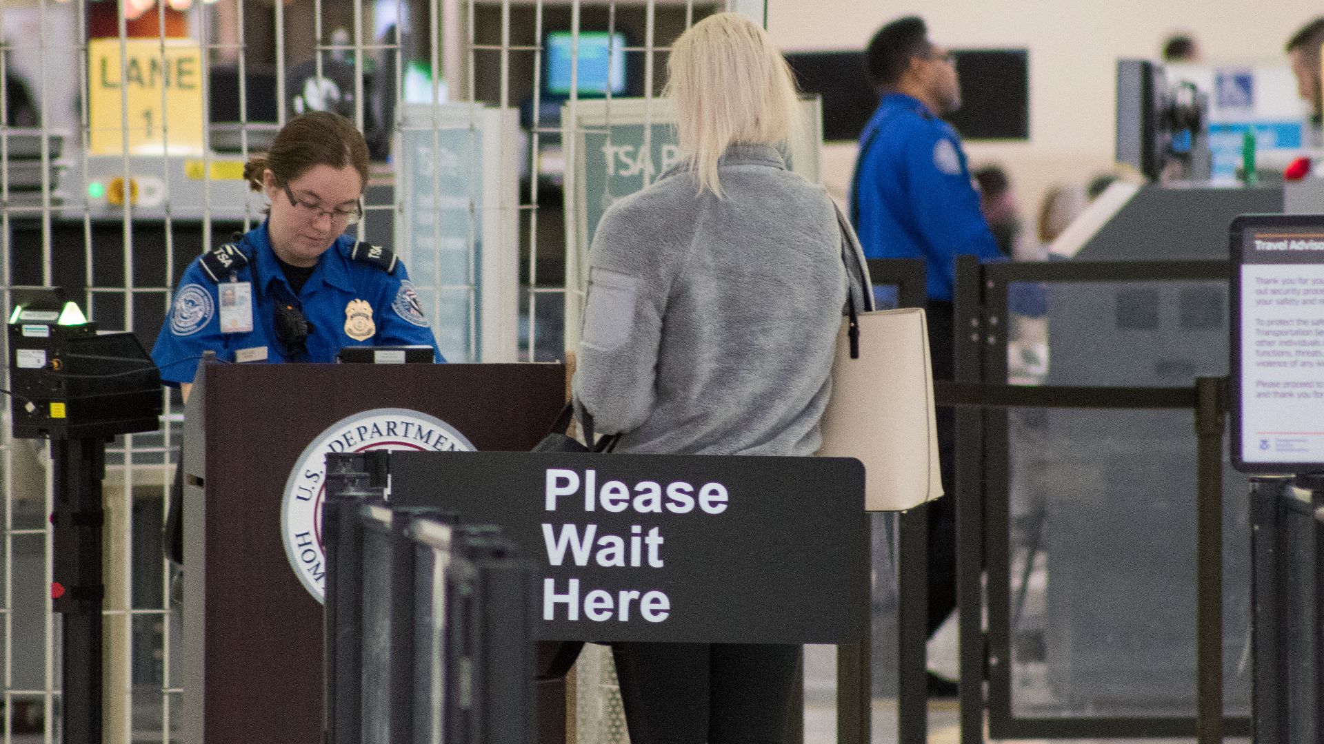 A Transportation Security Administration agent at a checkpoint verifying passenger identification, John Glenn Columbus International Airport