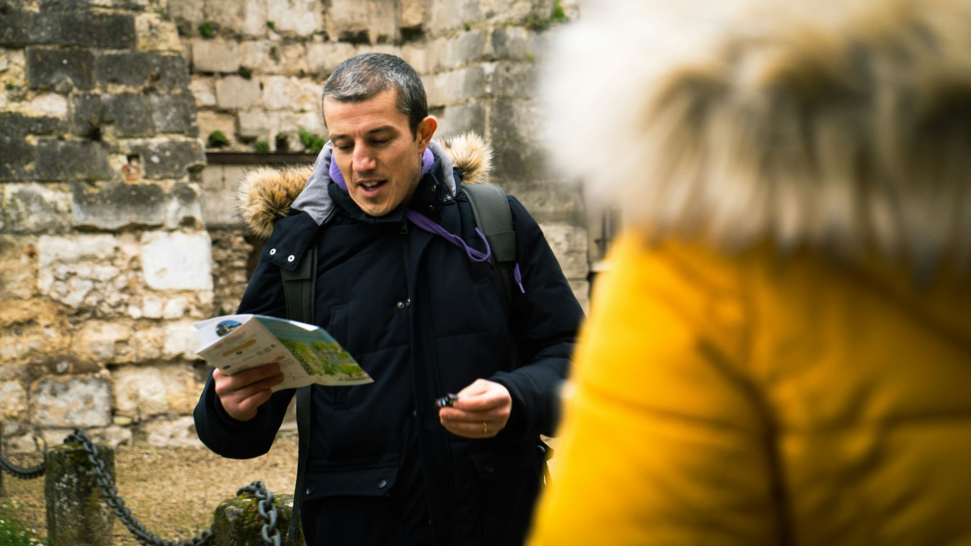 a man standing in front of a stone wall