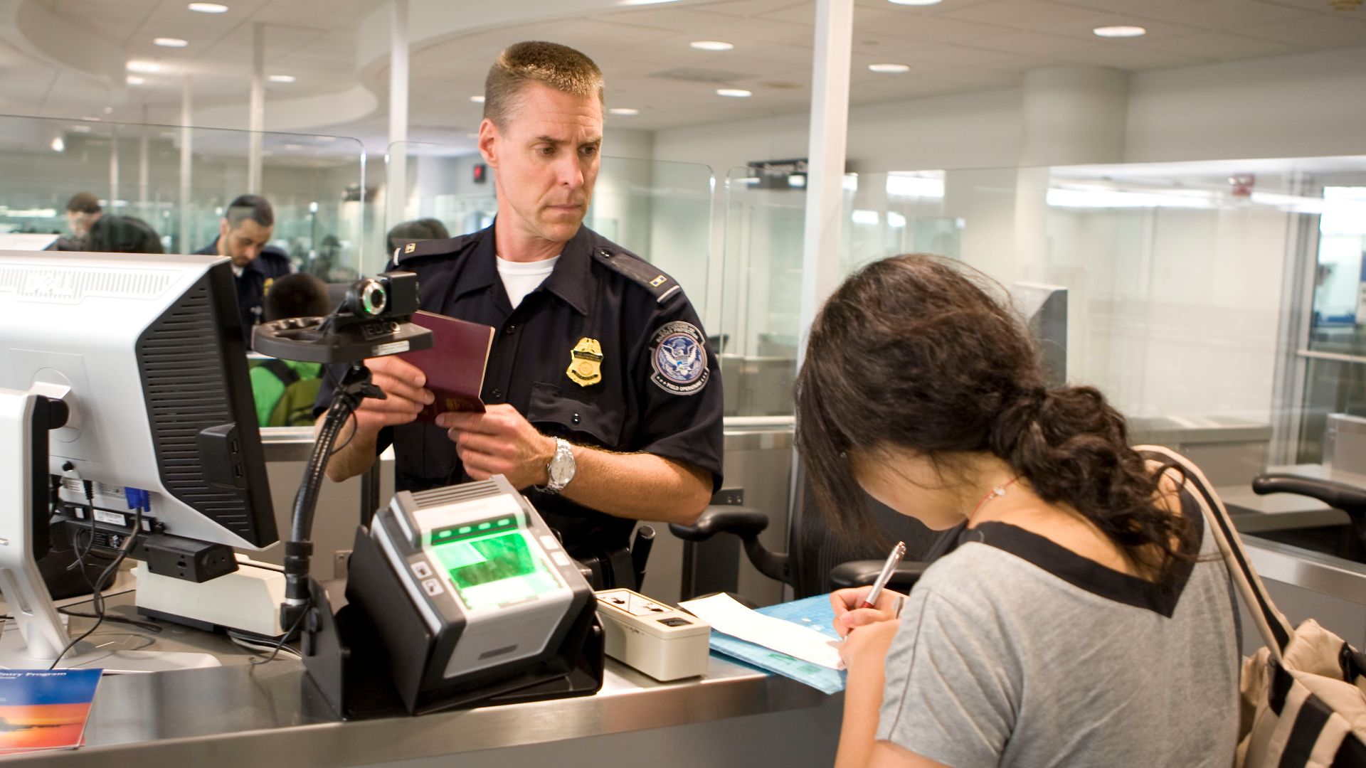 CBP Officer processes a passenger into the United States at an airport. Photo by James Tourtellotte