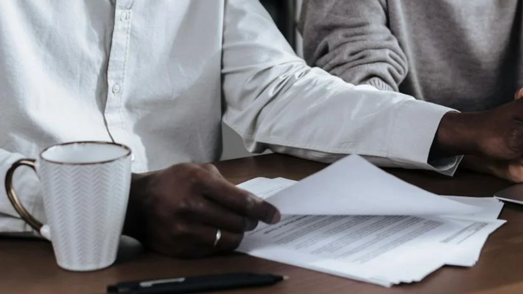 Couple Holding Hands While Reading Documents