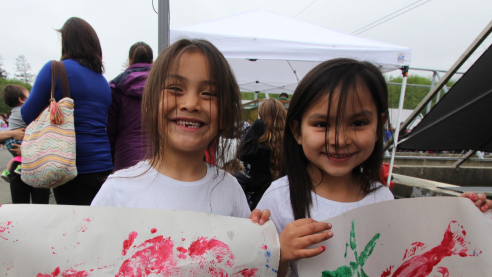 Two girls hold fish prints during a Community Fishing Day at the Makah National Fish Hatchery in Washington in the United States.