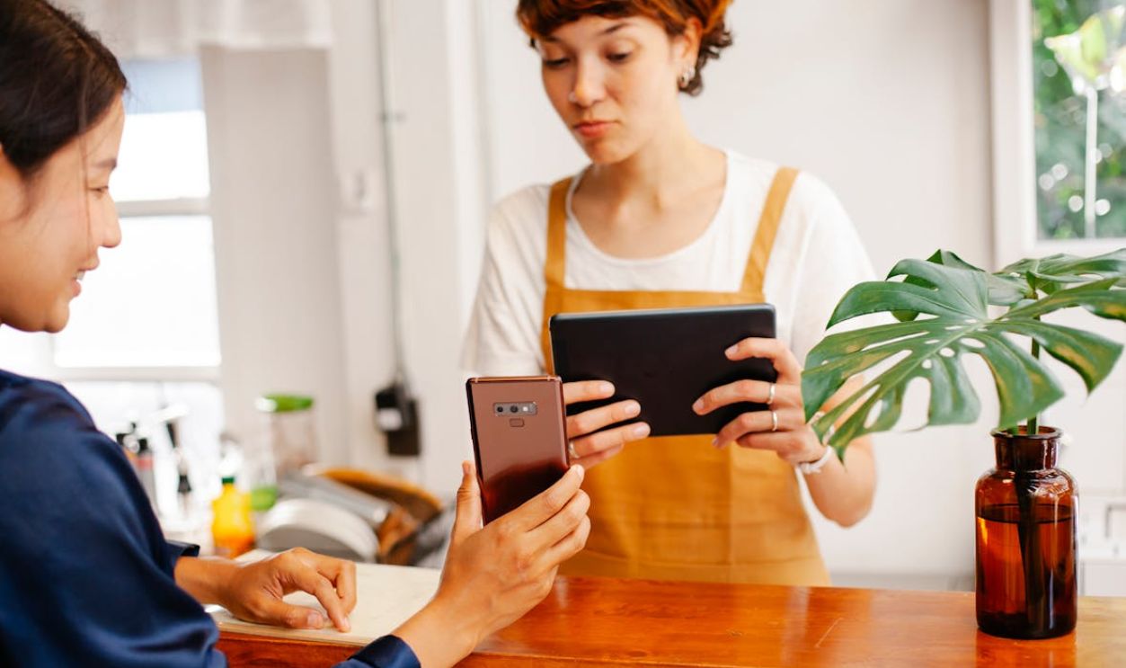 Crop multiracial cafe colleagues sharing smartphone at counter