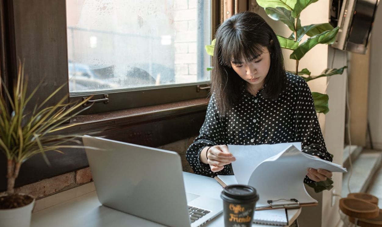 Woman in Black and White Long Sleeve Shirt Looking On A Paperwork