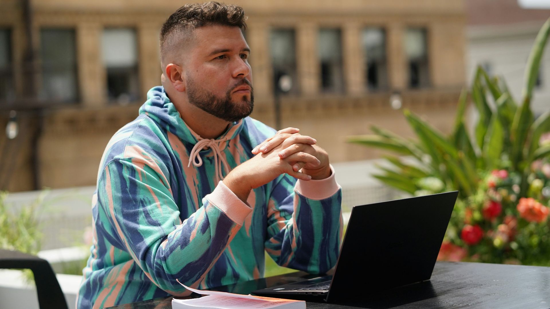 man in blue and white tribal print hoodie sitting beside black laptop computer