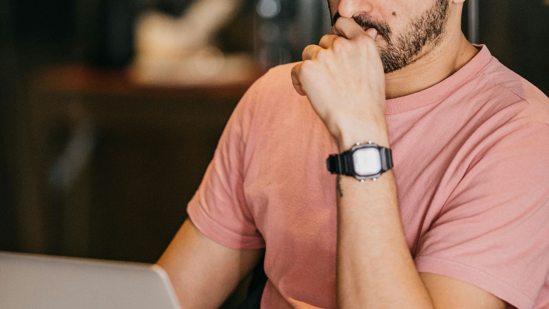 a man sitting at a table with a laptop and a cup