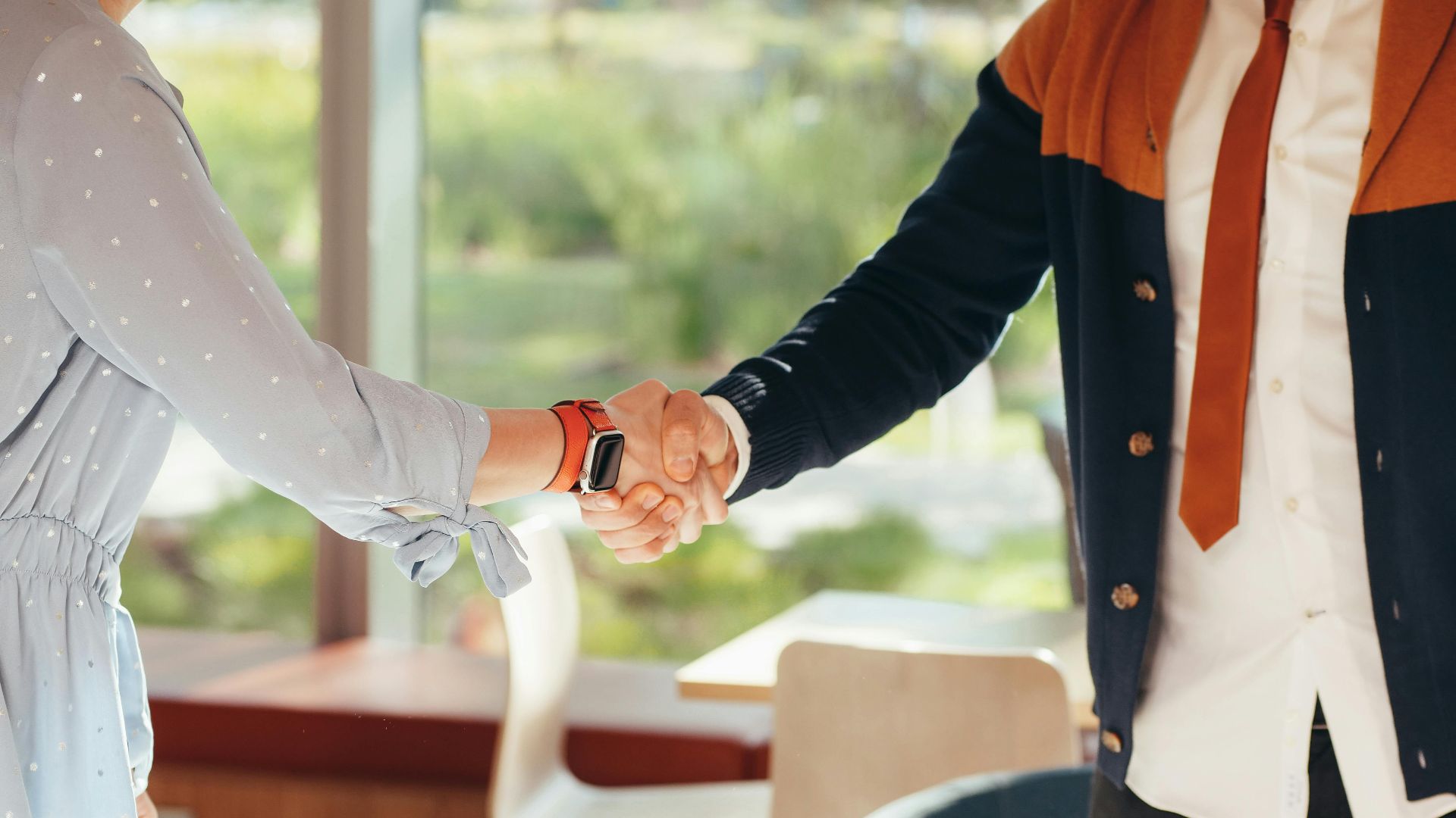 Close-up of colleagues shaking hands in an office, symbolizing teamwork and collaboration.