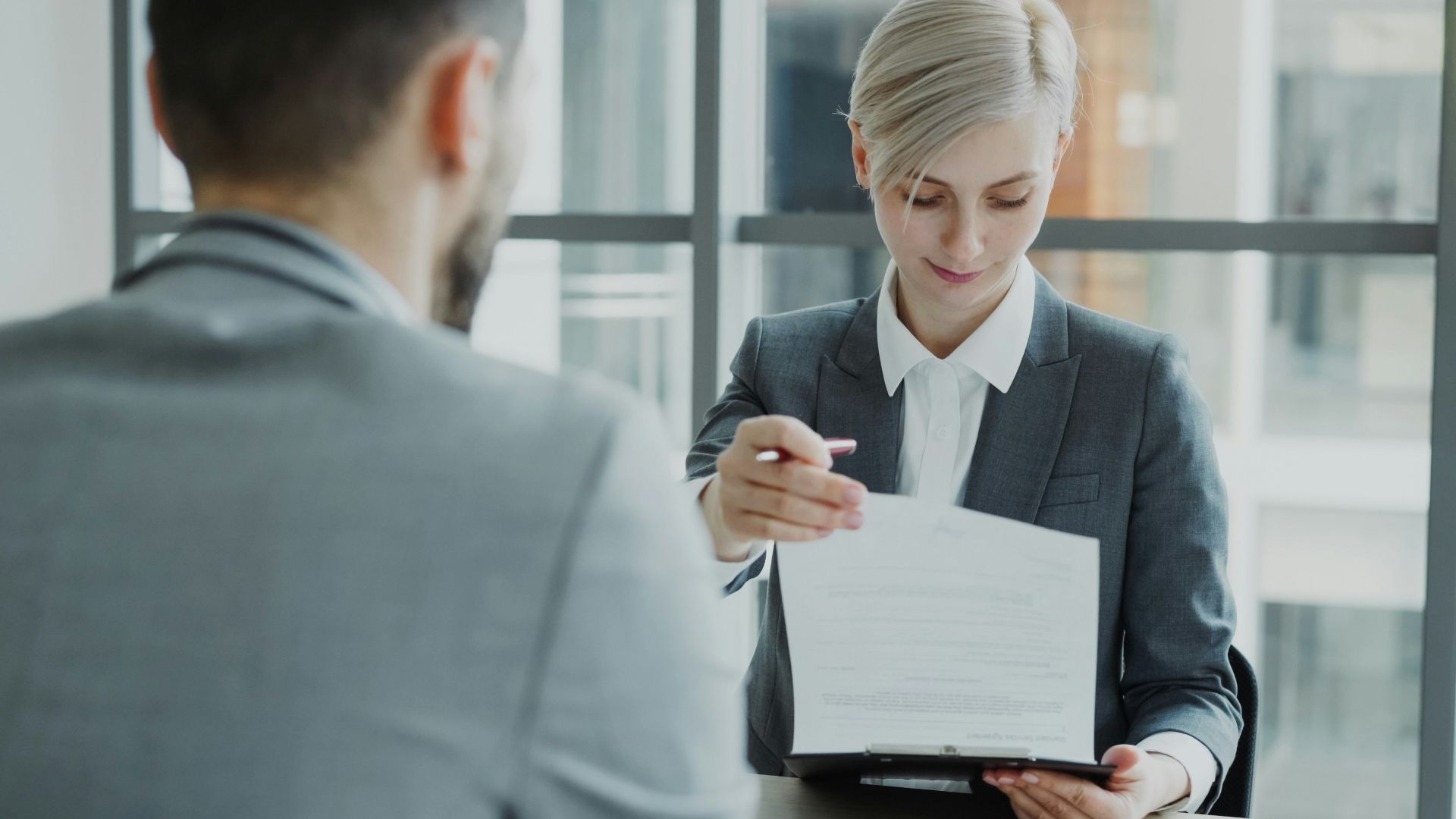 Woman in suit shows document to man