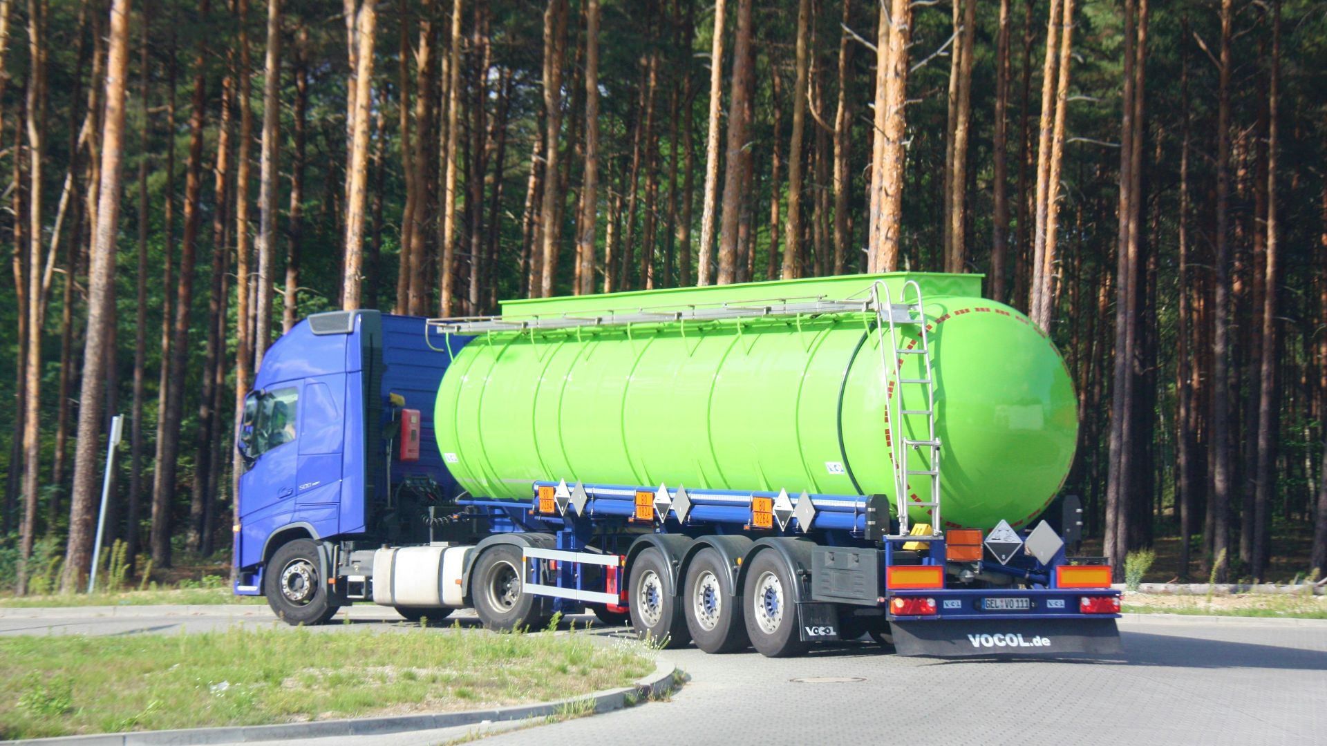 a large green tanker truck driving down a road