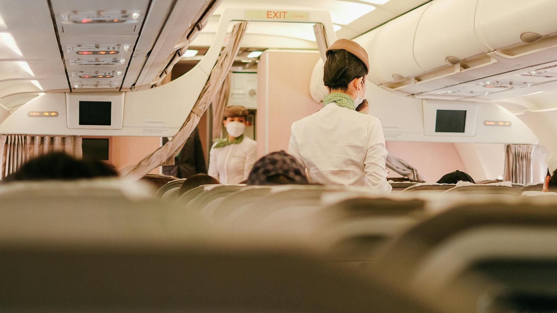 Flight attendants attending to passengers in an airplane cabin during a flight.