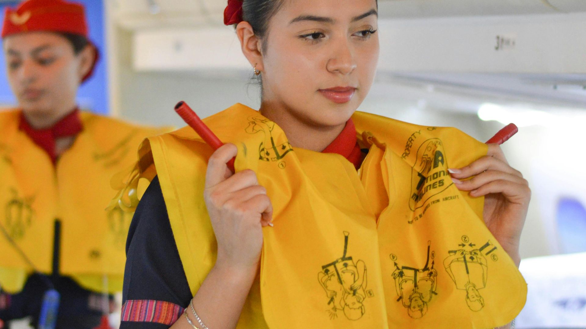 Airline flight attendants conduct a safety demonstration inside the aircraft cabin.