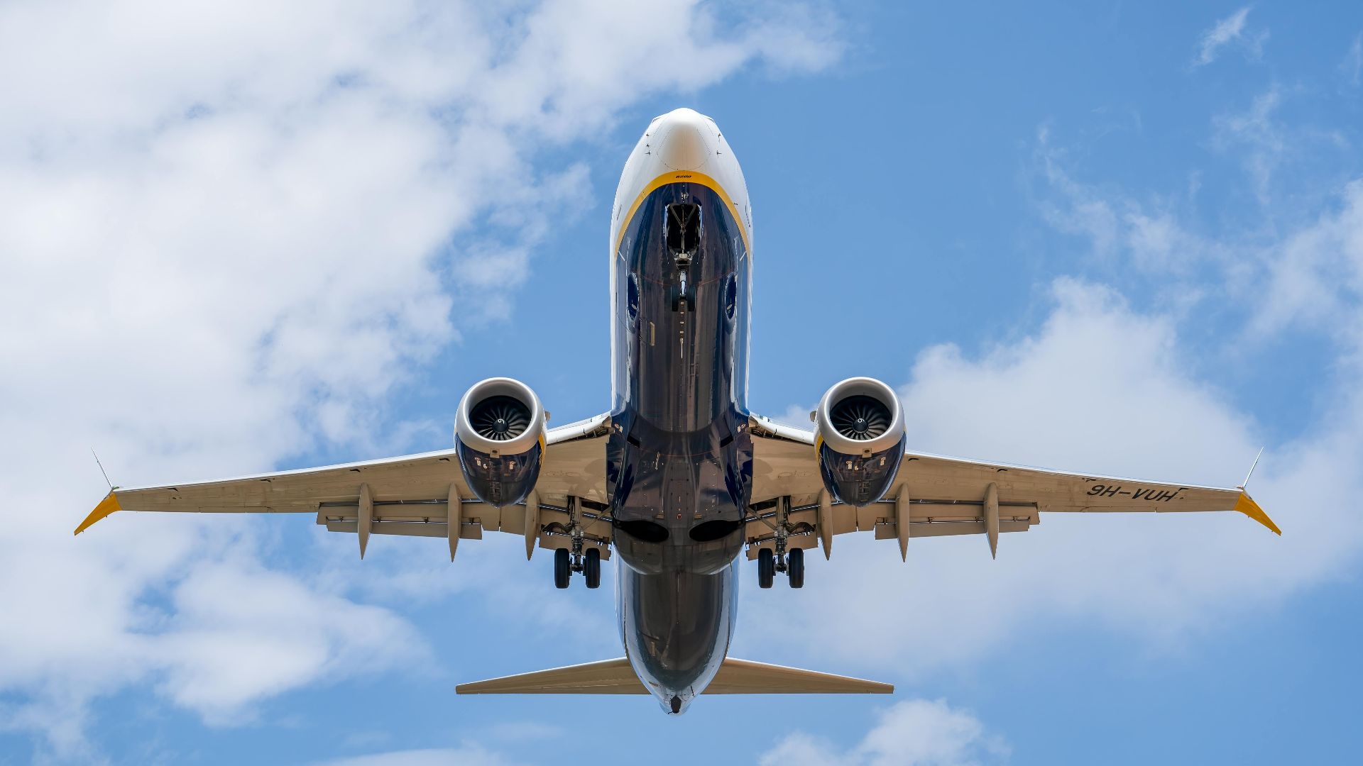 A low-angle shot of a commercial airplane flying against a clear blue sky in Manises, Spain.