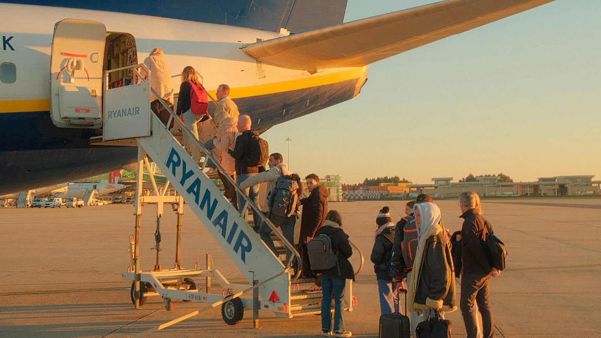 Travelers board a Ryanair plane at sunset in Porto, capturing the essence of budget travel.