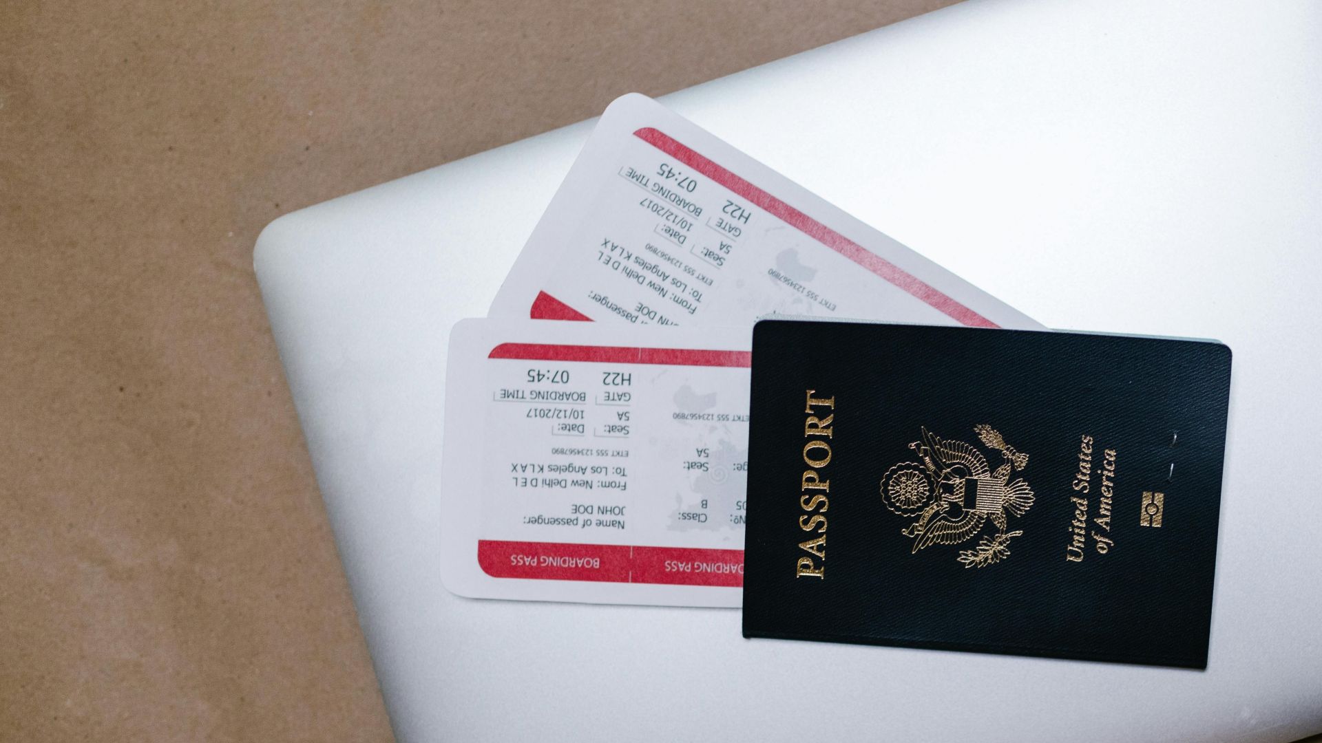 Close-up of a passport and boarding passes on a laptop, symbolizing travel preparation.