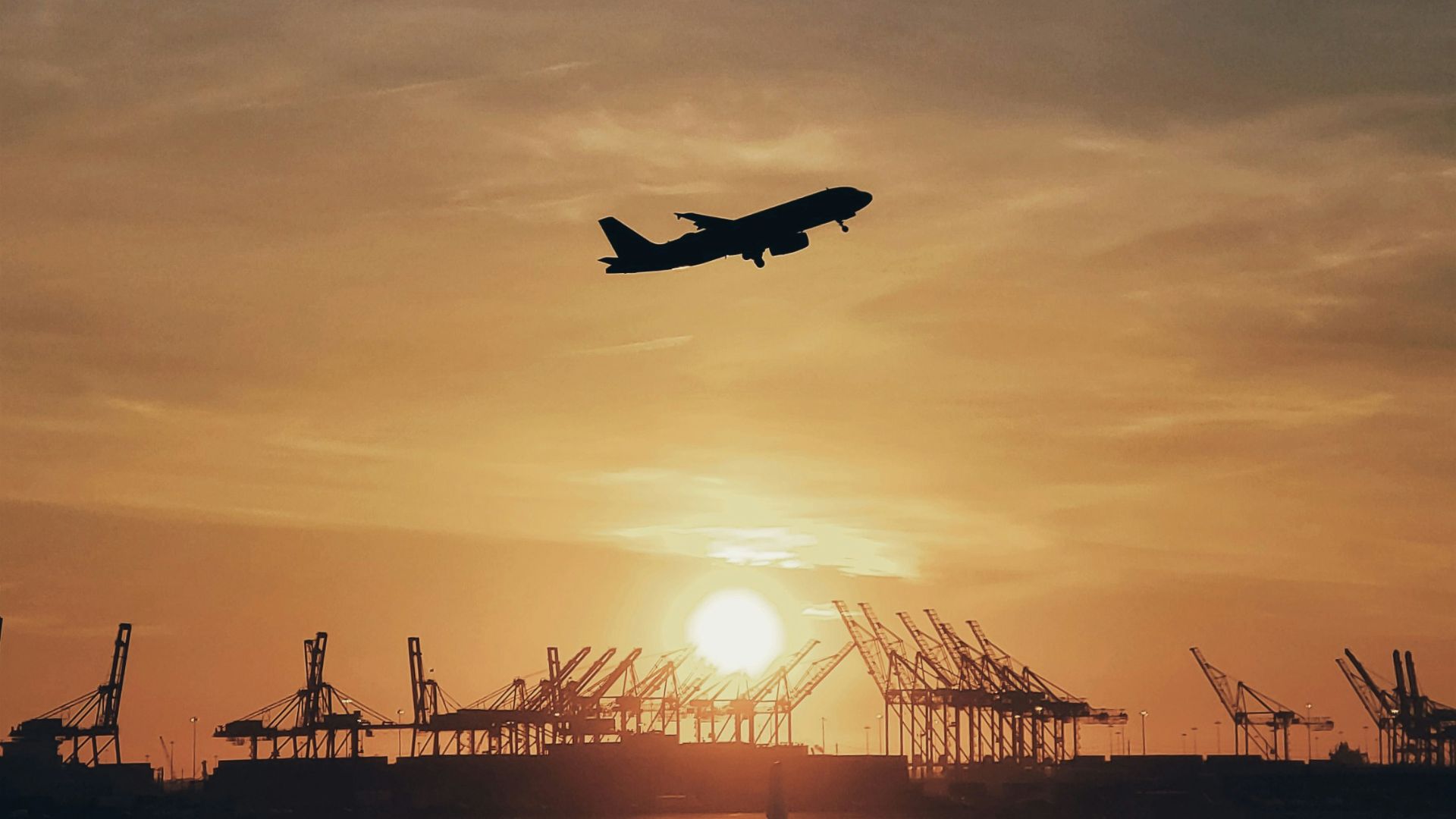 silhouette of airplane flying over the people during sunset
