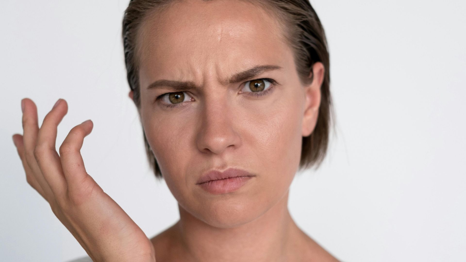 A confused young woman with a questioning facial expression on a white background.