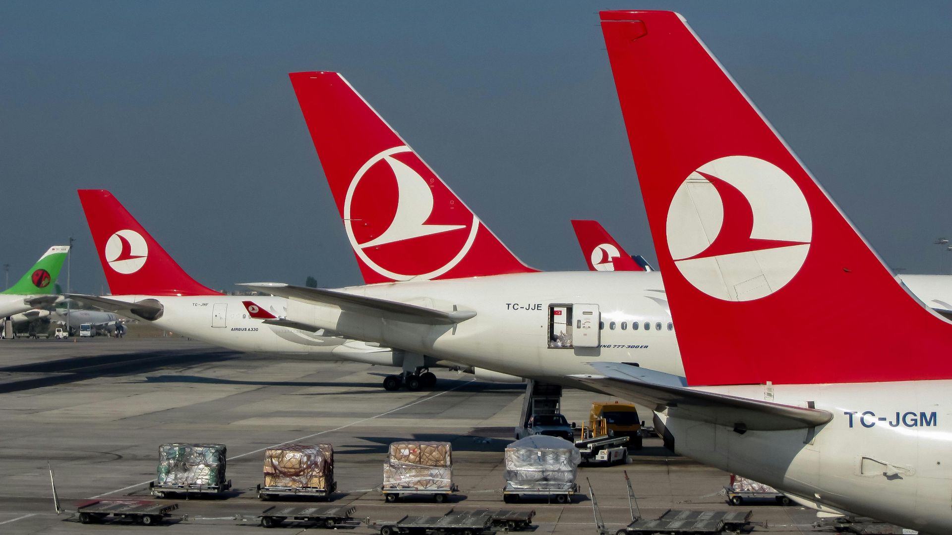 Turkish Airlines aircraft on the tarmac at Istanbul Airport, showcasing vibrant red tails under clear skies.