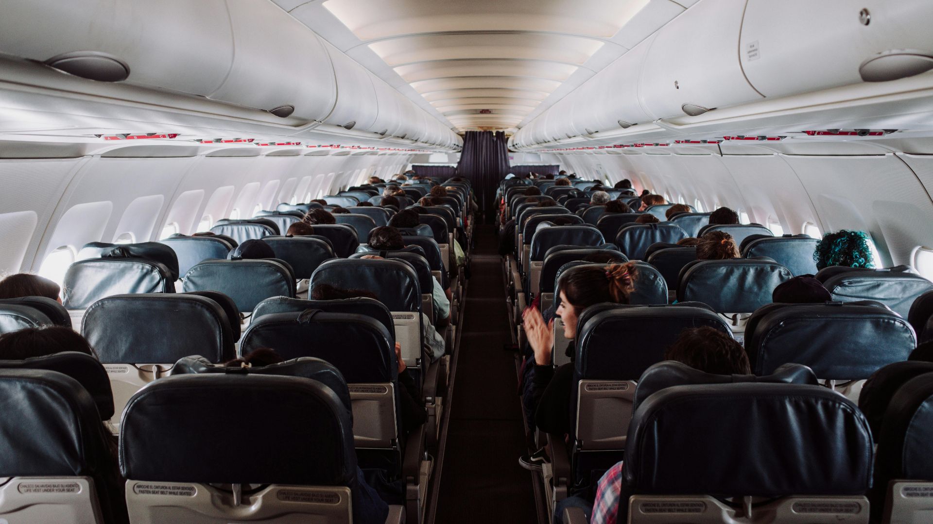 A view of passengers seated inside a commercial airplane cabin during flight.