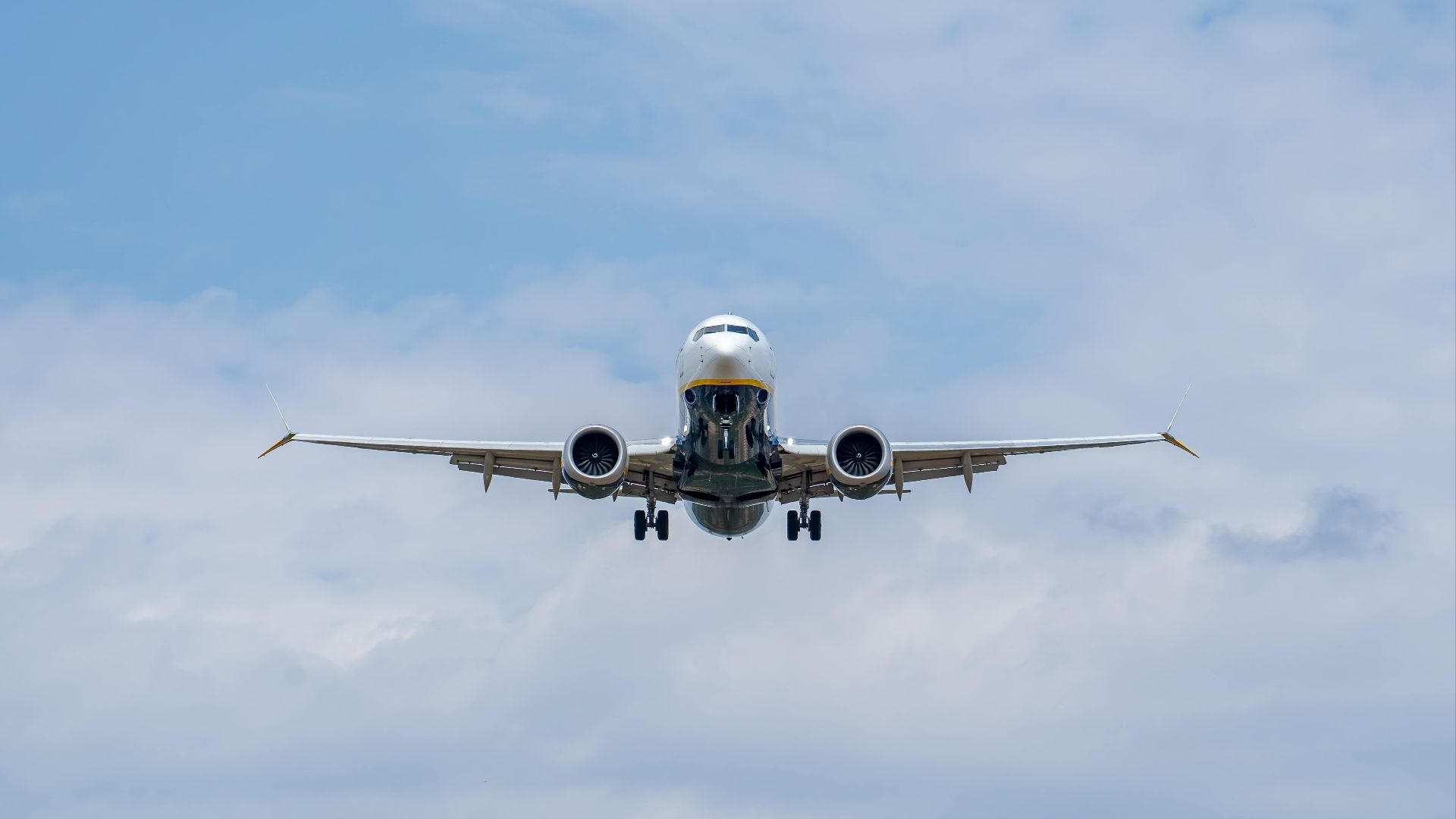 Airplane descending against a blue sky at Manises Airport in Spain, showcasing modern civil aviation.